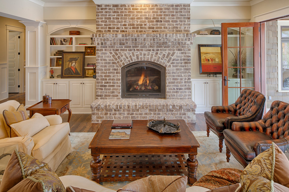 Photo of a large traditional enclosed living room in Atlanta with beige walls, medium hardwood floors, a standard fireplace and a brick fireplace surround.