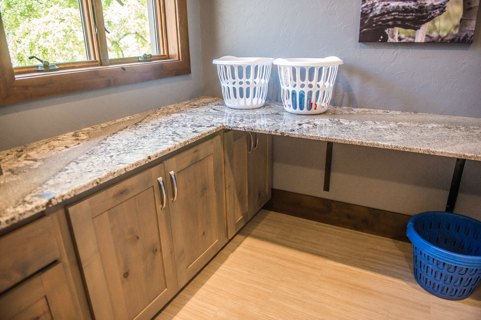 Utility room - huge rustic u-shaped gray floor utility room idea with an undermount sink, flat-panel cabinets, light wood cabinets, granite countertops, blue walls, a side-by-side washer/dryer and multicolored countertops