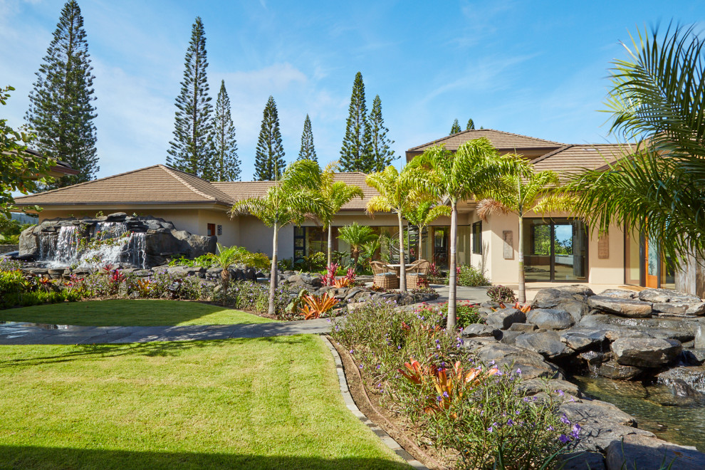 This is an example of an expansive contemporary front yard full sun garden in Hawaii with with waterfall and natural stone pavers.