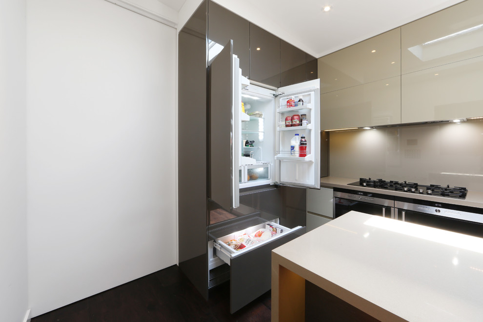 Design ideas for a contemporary l-shaped eat-in kitchen in Melbourne with a drop-in sink, flat-panel cabinets, white cabinets, quartz benchtops, glass sheet splashback and stainless steel appliances.