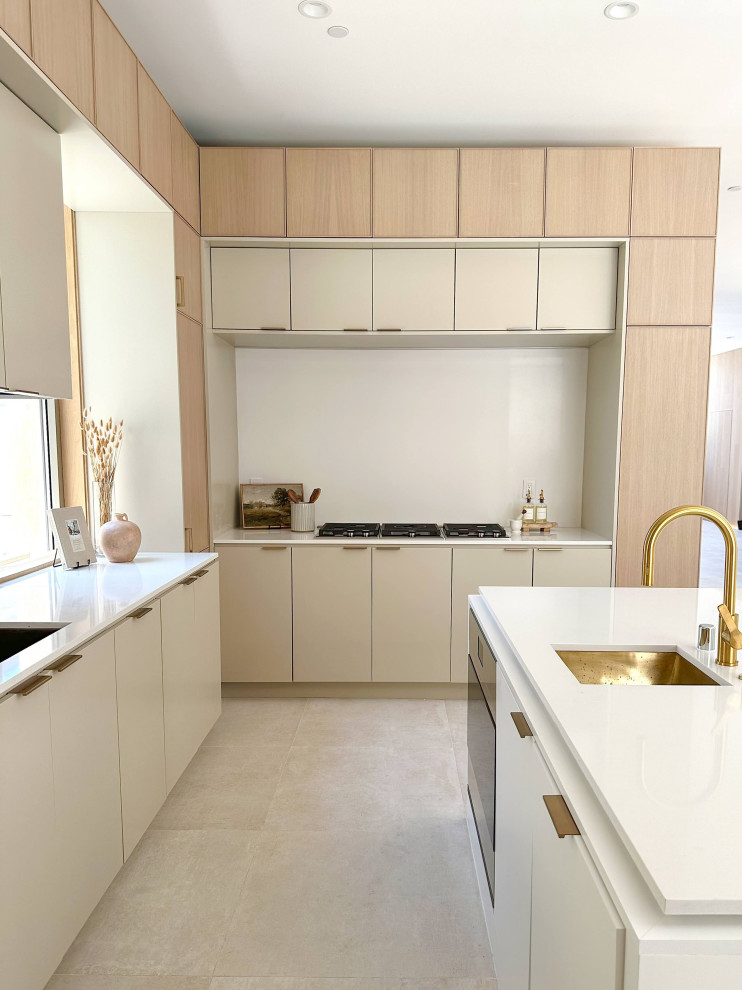 Design ideas for a medium sized modern l-shaped kitchen pantry in Orange County with a belfast sink, shaker cabinets, light wood cabinets, laminate countertops, white splashback, ceramic splashback, stainless steel appliances, ceramic flooring, an island, multi-coloured floors, white worktops and a vaulted ceiling.