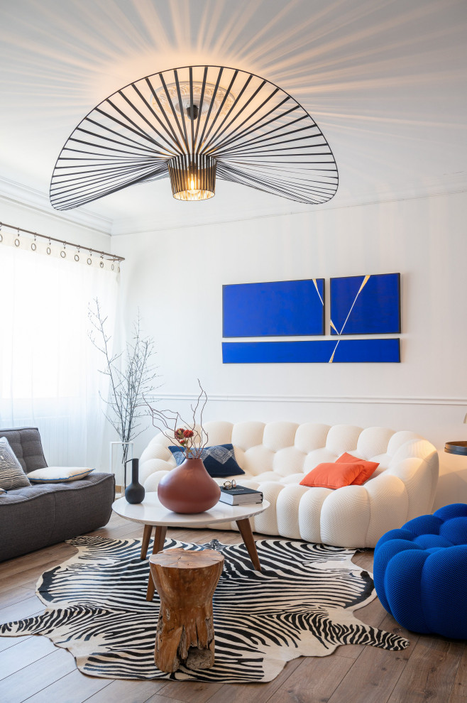 Cette image montre un salon design de taille moyenne et ouvert avec un mur blanc, parquet clair, un sol beige et éclairage.