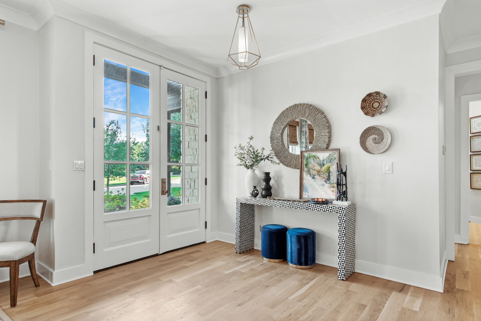 Example of a large transitional light wood floor hallway design with white walls, a standard fireplace and a plaster fireplace