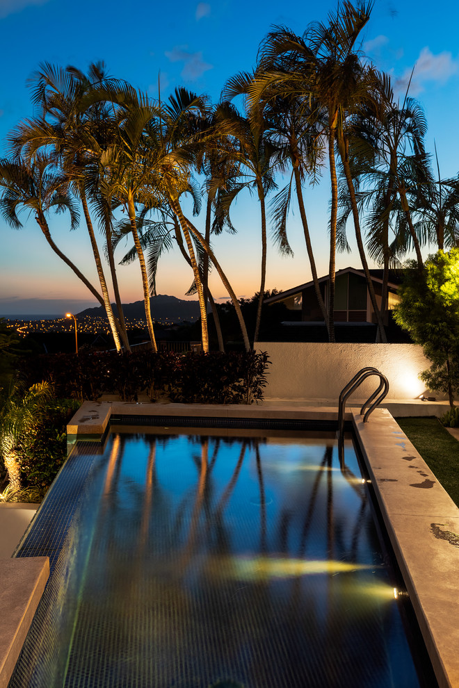 This is an example of a mid-sized modern backyard custom-shaped infinity pool in Hawaii with tile.