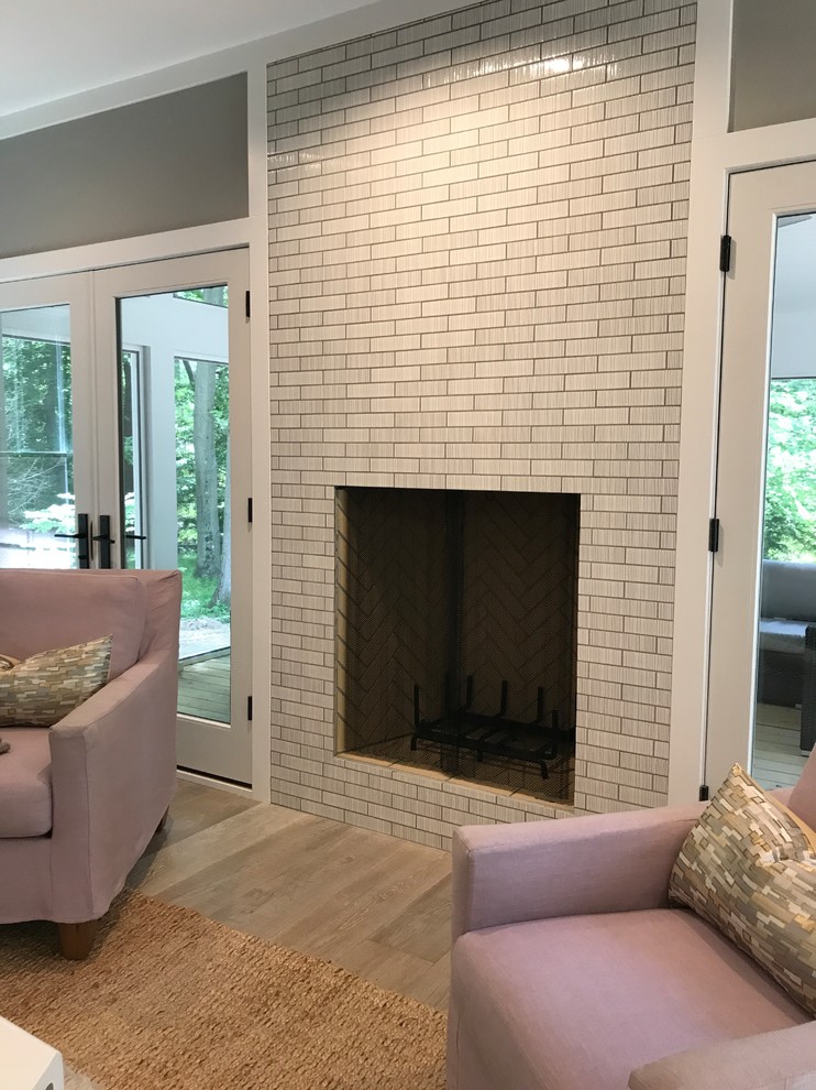 Inspiration for a mid-sized transitional open concept family room with grey walls, light hardwood floors, a standard fireplace, a tile fireplace surround and beige floor.