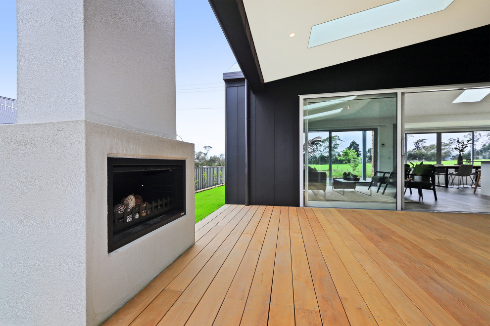 Photo of a medium sized modern conservatory in Napier-Hastings with light hardwood flooring, a standard fireplace, a concrete fireplace surround, a skylight and brown floors.