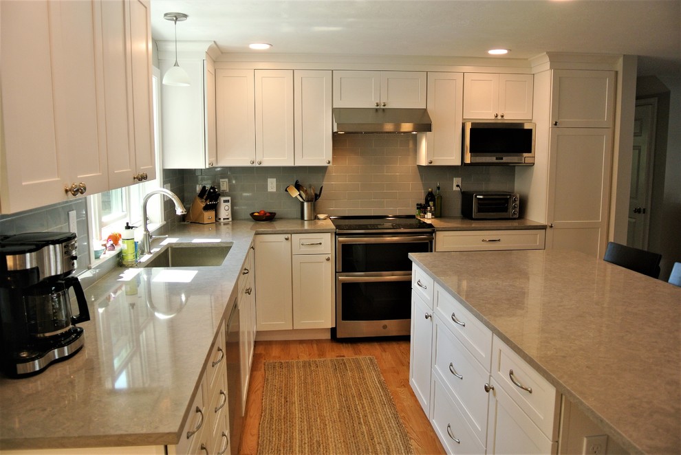 Kitchen - transitional light wood floor kitchen idea in Boston with an undermount sink, shaker cabinets, white cabinets, quartz countertops, gray backsplash, subway tile backsplash, stainless steel appliances, an island and gray countertops