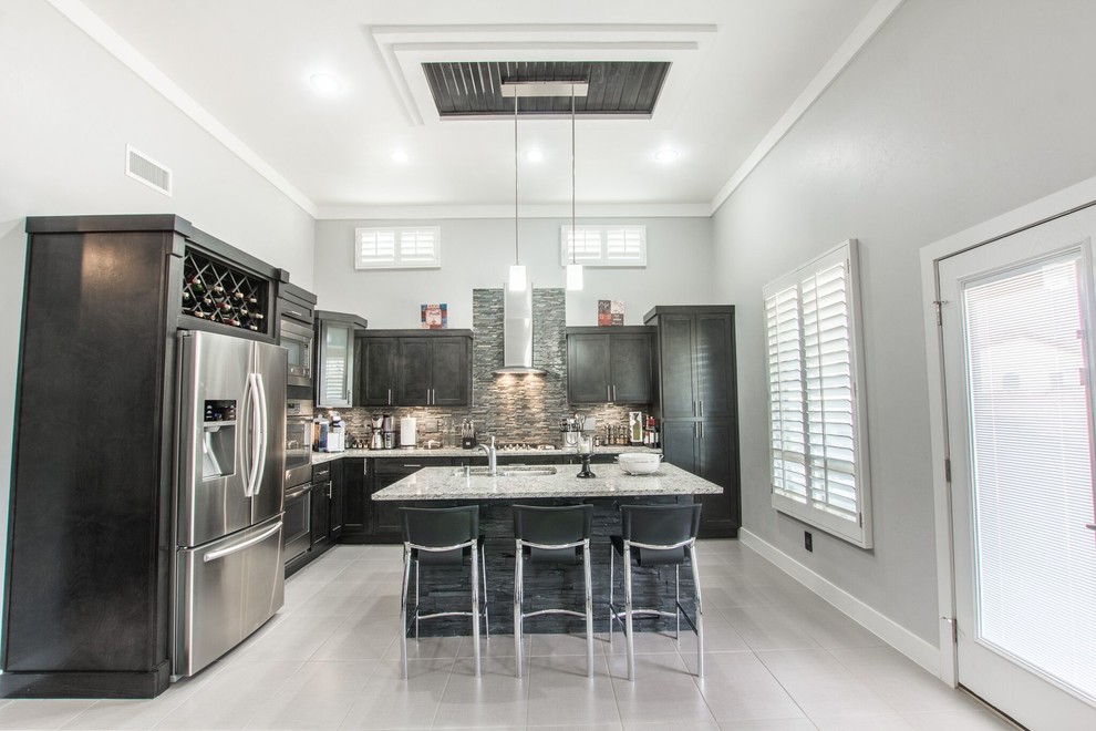 Mid-sized transitional u-shaped ceramic tile eat-in kitchen photo in Austin with a double-bowl sink, flat-panel cabinets, dark wood cabinets, granite countertops, gray backsplash, glass tile backsplash, stainless steel appliances and an island