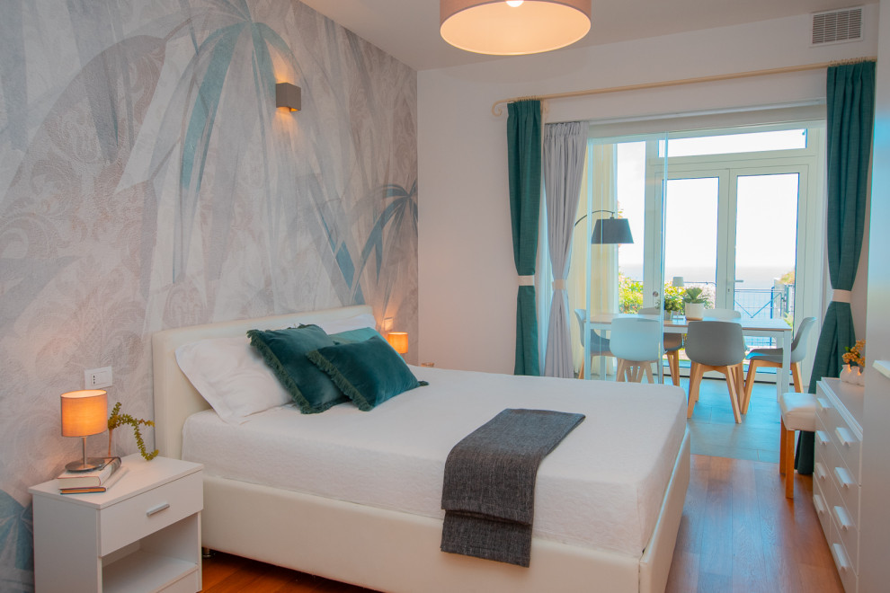 Foto di una camera matrimoniale mediterranea di medie dimensioni con pareti bianche, parquet chiaro e carta da parati