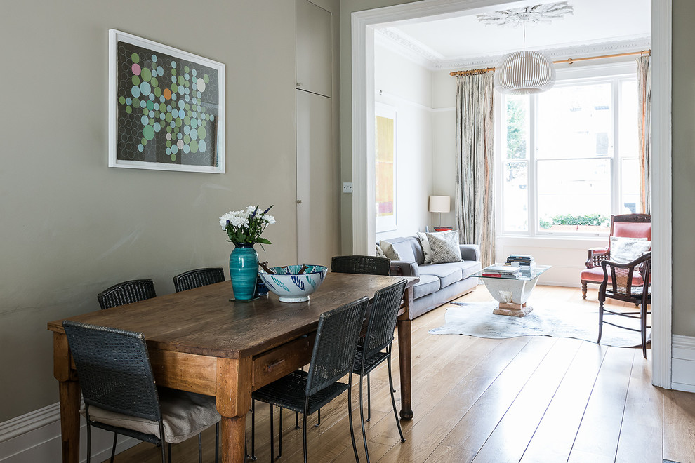 Photo of a transitional open plan dining in London with grey walls and light hardwood floors.