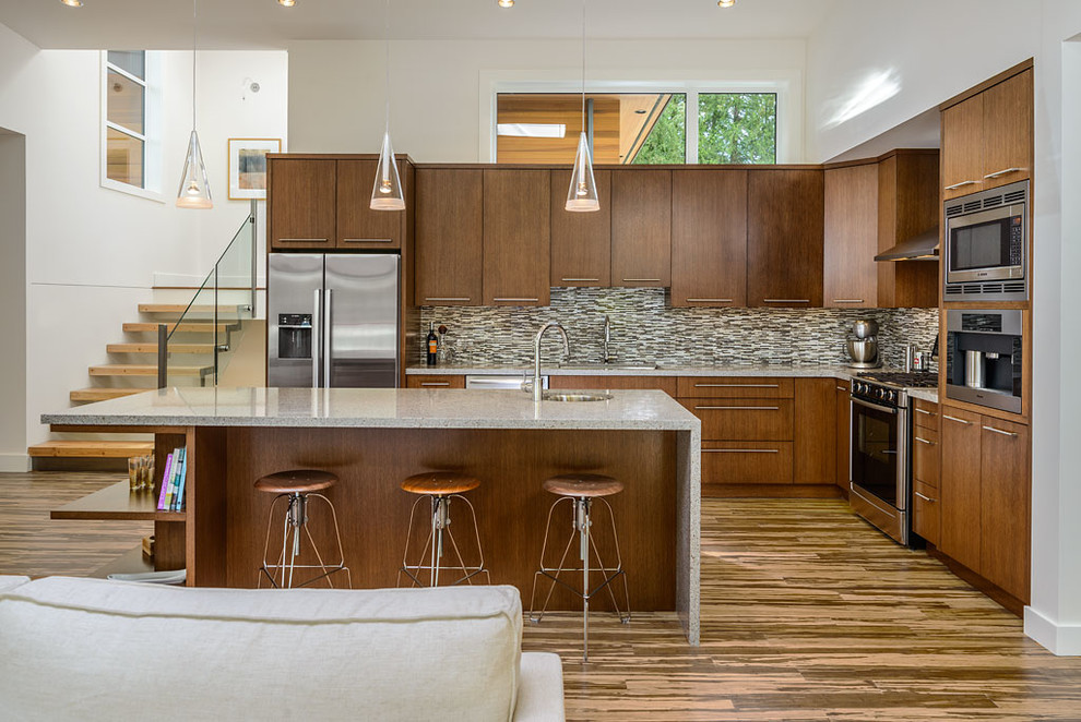 Photo of a contemporary l-shaped open plan kitchen in Vancouver with flat-panel cabinets, dark wood cabinets, multi-coloured splashback, matchstick tile splashback and stainless steel appliances.