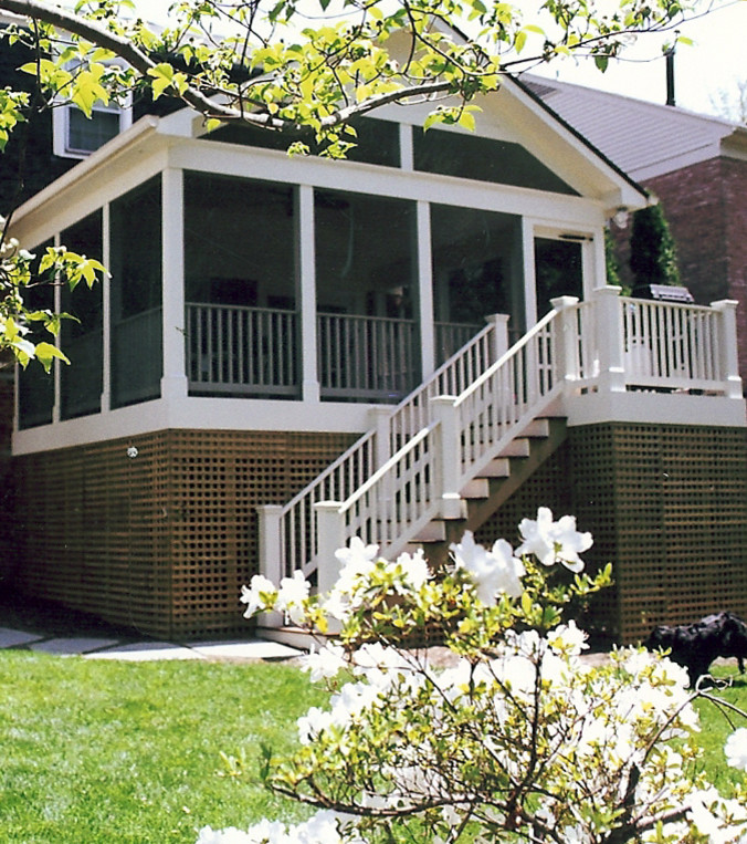 This is an example of a mid-sized traditional screened-in back porch design in DC Metro with decking and a roof extension.