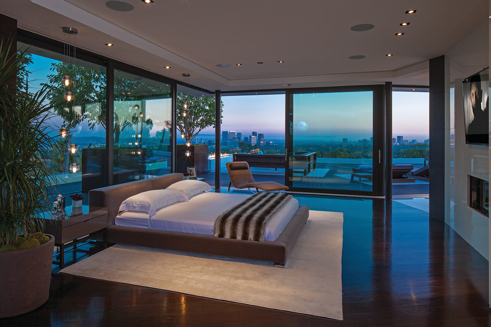 Expansive contemporary master bedroom in Los Angeles with a standard fireplace and recessed.