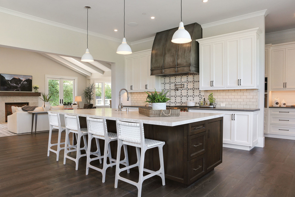 Large beach style open plan kitchen in San Francisco with with island, shaker cabinets, white cabinets, multi-coloured splashback, dark hardwood floors, brown floor and grey benchtop.