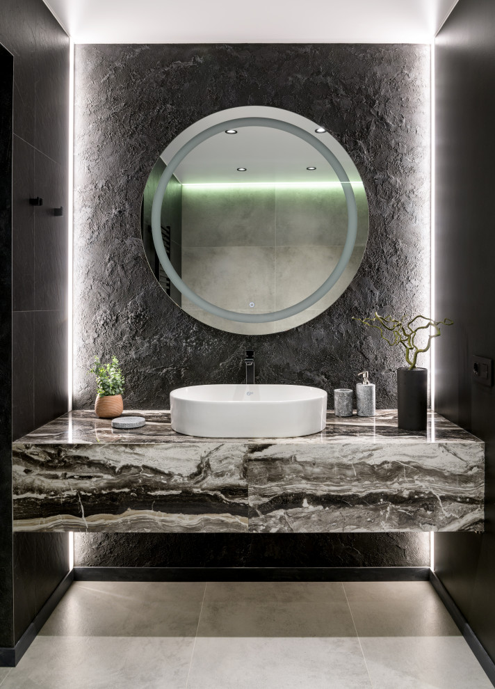 This is an example of a large contemporary 3/4 bathroom in Novosibirsk with flat-panel cabinets, grey cabinets, an undermount tub, an alcove shower, a wall-mount toilet, gray tile, porcelain tile, black walls, porcelain floors, a drop-in sink, tile benchtops, grey floor, a hinged shower door, grey benchtops, a single vanity and a floating vanity.