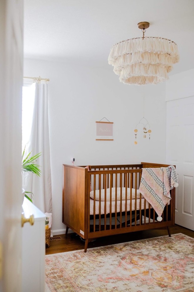 Design ideas for a mid-sized eclectic nursery for girls in Denver with white walls, dark hardwood floors and brown floor.