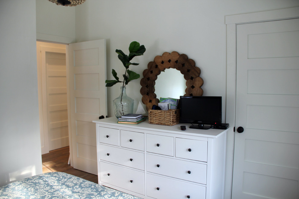 This is an example of a mid-sized beach style guest bedroom in Other with white walls, light hardwood floors and no fireplace.