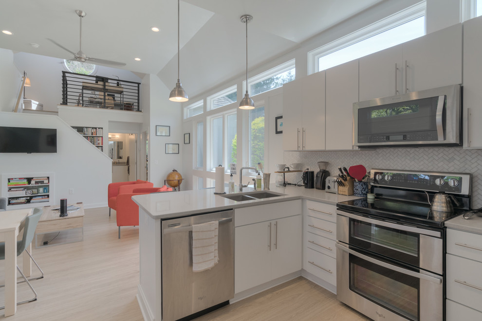 Example of a small minimalist l-shaped vinyl floor and beige floor open concept kitchen design with an undermount sink, flat-panel cabinets, white cabinets, quartz countertops, gray backsplash, marble backsplash and stainless steel appliances