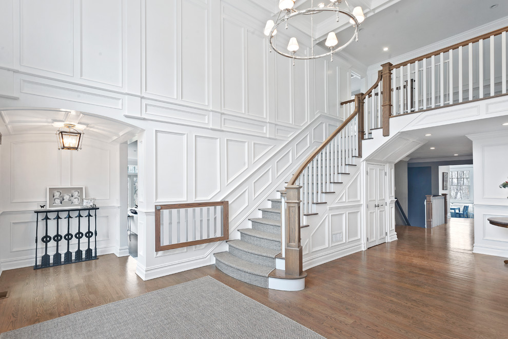This is an example of a large traditional carpeted l-shaped staircase in New York with carpet risers and wood railing.