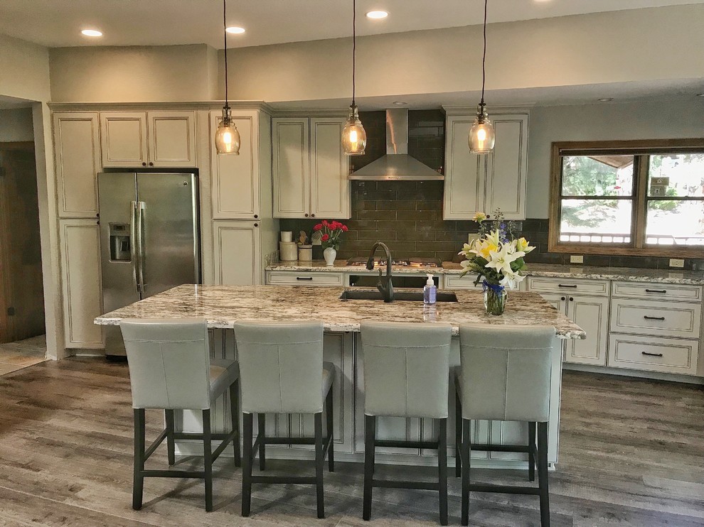 Design ideas for a large transitional l-shaped eat-in kitchen in Phoenix with a farmhouse sink, white cabinets, granite benchtops, brown splashback, subway tile splashback, stainless steel appliances, porcelain floors, with island, grey floor, beige benchtop and recessed-panel cabinets.