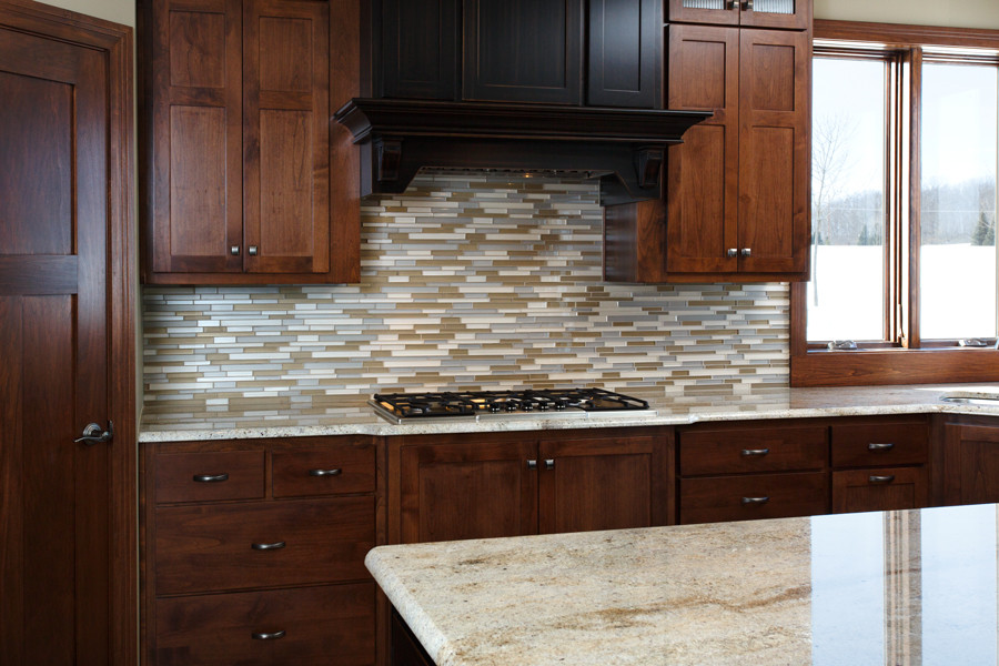 Example of a large transitional u-shaped eat-in kitchen design with recessed-panel cabinets, dark wood cabinets, granite countertops, multicolored backsplash, glass tile backsplash, colored appliances and an island