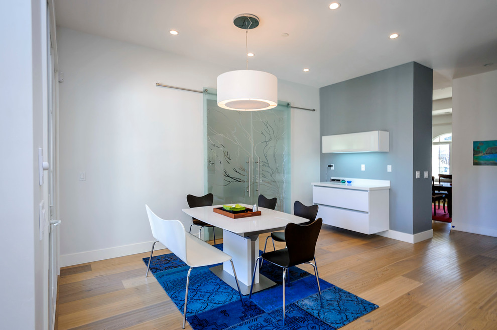 This is an example of a mid-sized modern kitchen/dining combo in San Francisco with white walls and light hardwood floors.