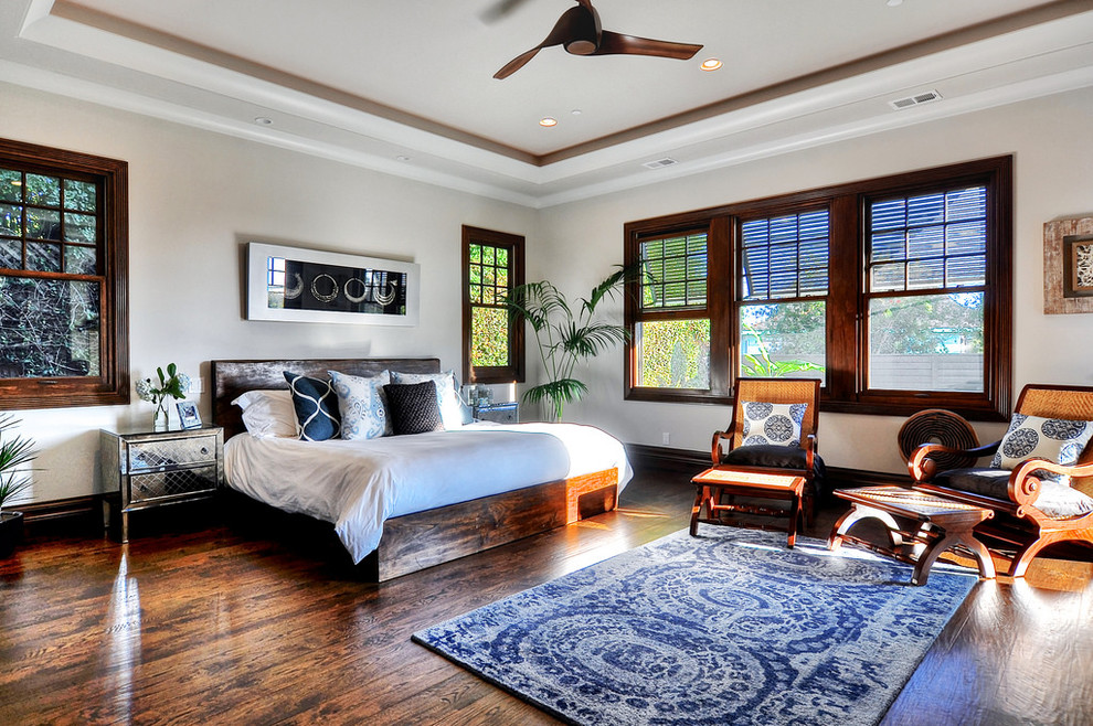 Tropical master bedroom in Los Angeles with white walls and dark hardwood floors.