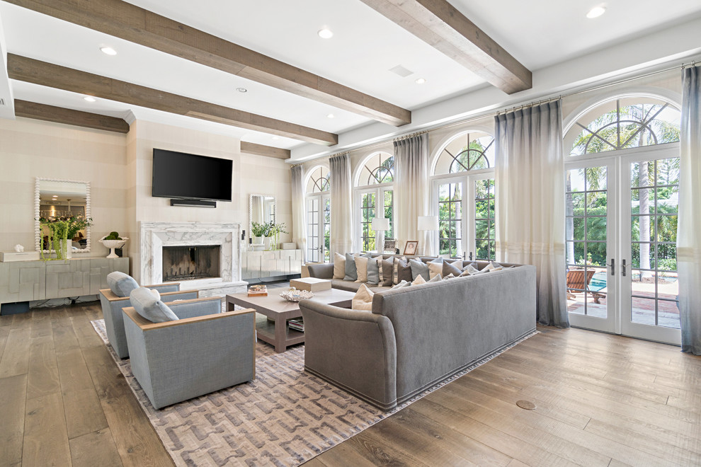 Large contemporary open plan games room in Miami with beige walls, dark hardwood flooring, a standard fireplace, a stone fireplace surround, a wall mounted tv, brown floors, exposed beams and wallpapered walls.