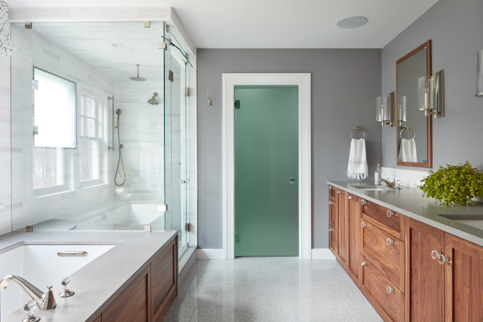 Inspiration for a mid-sized transitional master bathroom in Boston with white tile, white walls, grey floor, medium wood cabinets, terrazzo floors, an undermount sink, a hinged shower door, grey benchtops, an enclosed toilet, a double vanity and a built-in vanity.