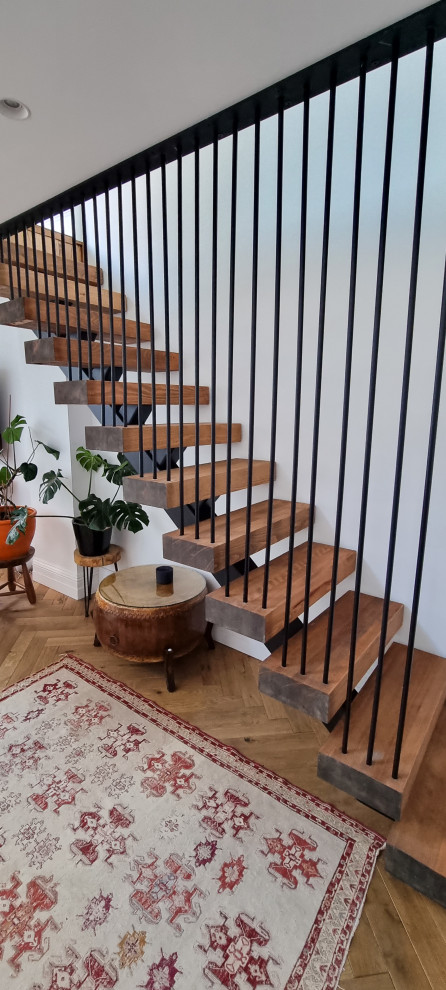 Idée de décoration pour un petit escalier flottant victorien avec des marches en bois, des contremarches en bois et un garde-corps en métal.