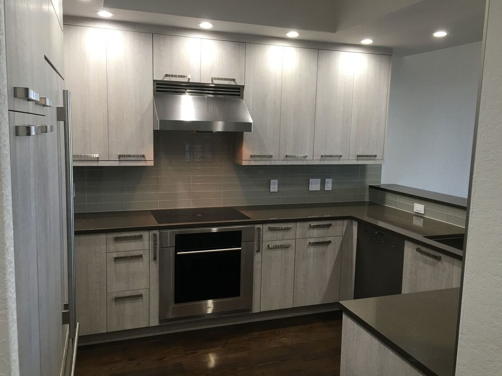 Photo of a contemporary eat-in kitchen in Orlando with an undermount sink, flat-panel cabinets, distressed cabinets, quartz benchtops, grey splashback, glass tile splashback, stainless steel appliances and medium hardwood floors.