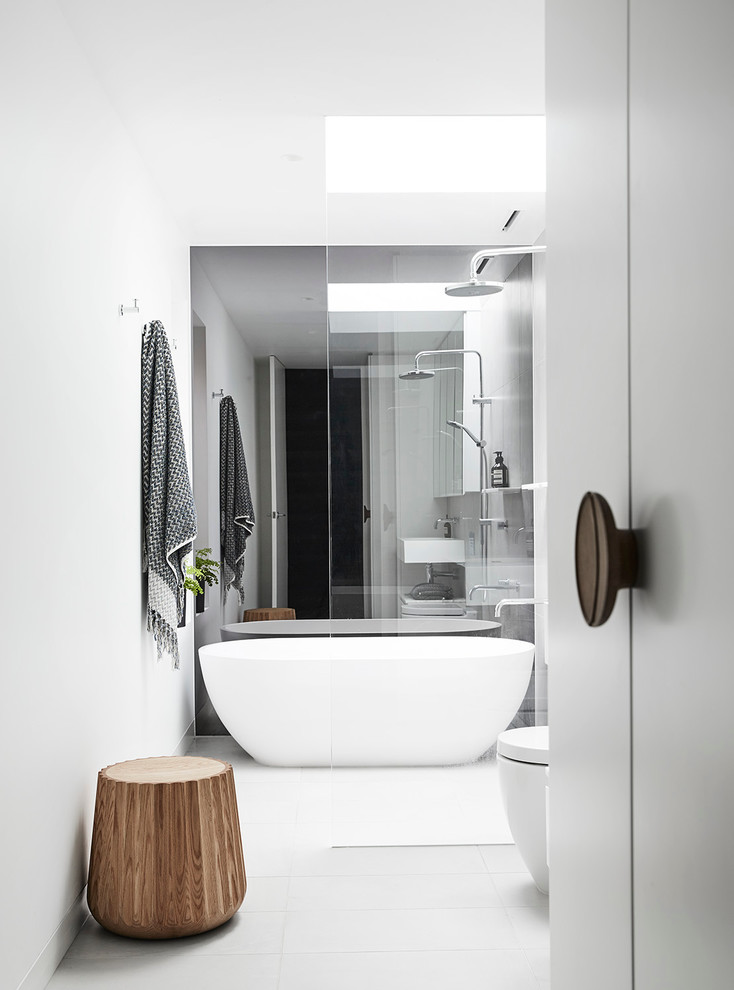 Mid-sized contemporary 3/4 bathroom in Melbourne with furniture-like cabinets, white cabinets, a freestanding tub, an open shower, a one-piece toilet, white tile, porcelain tile, white walls, porcelain floors, a drop-in sink and solid surface benchtops.
