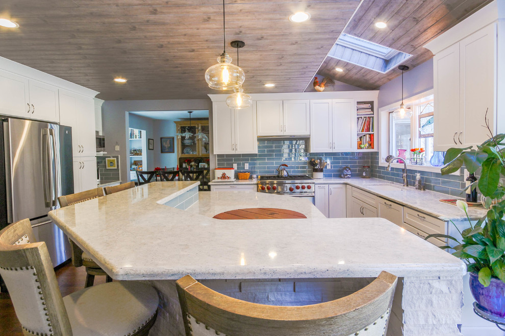 Large traditional u-shaped eat-in kitchen in Detroit with an undermount sink, shaker cabinets, white cabinets, quartz benchtops, blue splashback, glass tile splashback, stainless steel appliances, medium hardwood floors, with island, brown floor and grey benchtop.