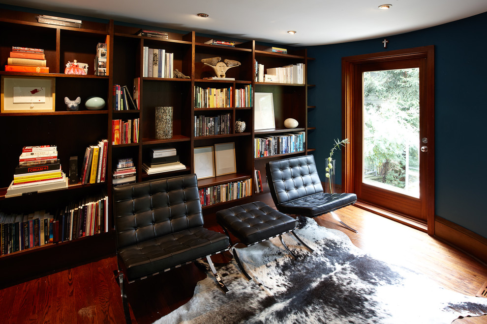 This is an example of a small contemporary open concept living room in Toronto with a library, blue walls, medium hardwood floors and no tv.