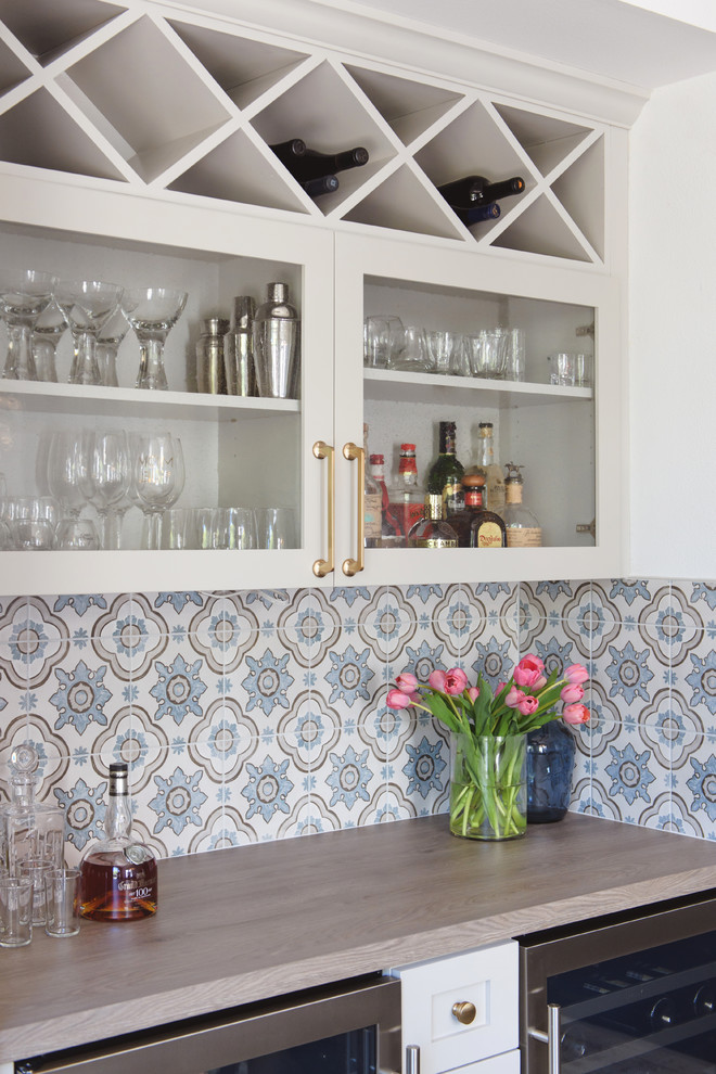 Mid-sized traditional galley home bar in San Diego with glass-front cabinets, white cabinets, wood benchtops, multi-coloured splashback and ceramic splashback.