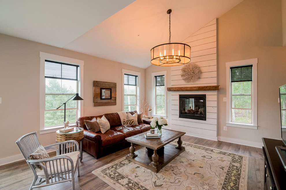 This is an example of a country open concept family room in Baltimore with grey walls, medium hardwood floors and a wood fireplace surround.
