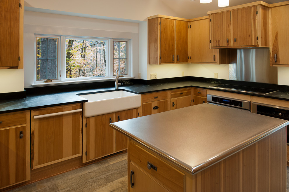 Inspiration for a rustic kitchen remodel with a farmhouse sink, flat-panel cabinets, soapstone countertops, stainless steel appliances and an island