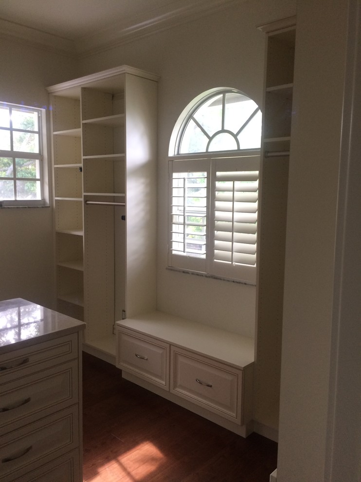 Large traditional gender-neutral walk-in wardrobe in Miami with raised-panel cabinets, white cabinets and dark hardwood floors.