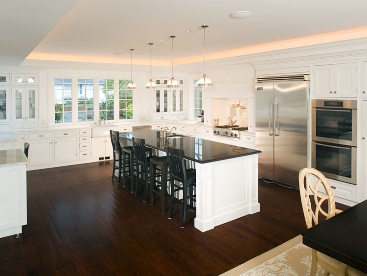 Large transitional u-shaped eat-in kitchen in Seattle with a farmhouse sink, white cabinets, white splashback, stainless steel appliances, dark hardwood floors, with island, shaker cabinets and marble benchtops.