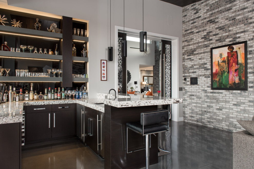 Photo of a contemporary u-shaped seated home bar in Las Vegas with an undermount sink, flat-panel cabinets, black cabinets, black splashback, glass sheet splashback, grey floor and multi-coloured benchtop.