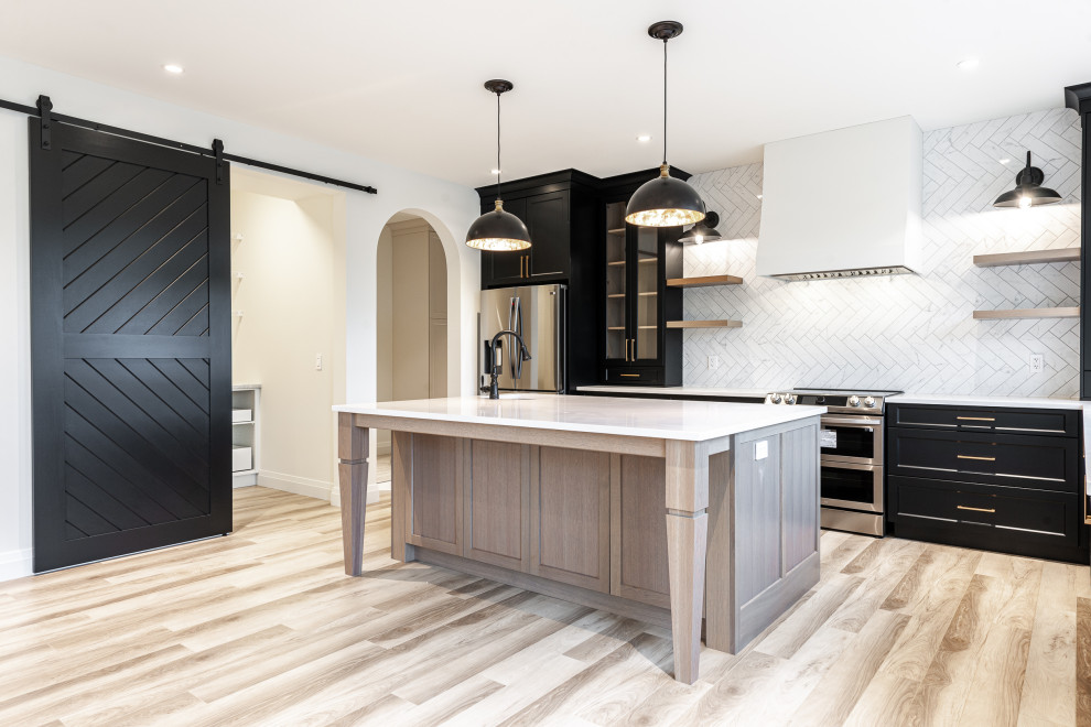 Eat-in kitchen - mid-sized transitional l-shaped laminate floor and brown floor eat-in kitchen idea in Toronto with an undermount sink, recessed-panel cabinets, black cabinets, quartz countertops, white backsplash, ceramic backsplash, stainless steel appliances, an island and white countertops