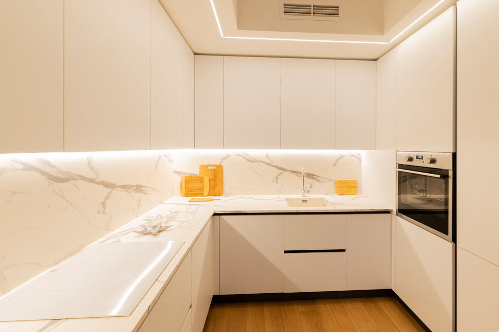 Bild på ett stort funkis vit vitt kök, med en nedsänkt diskho, släta luckor, vita skåp, bänkskiva i koppar, vitt stänkskydd, stänkskydd i porslinskakel, rostfria vitvaror, mellanmörkt trägolv och brunt golv