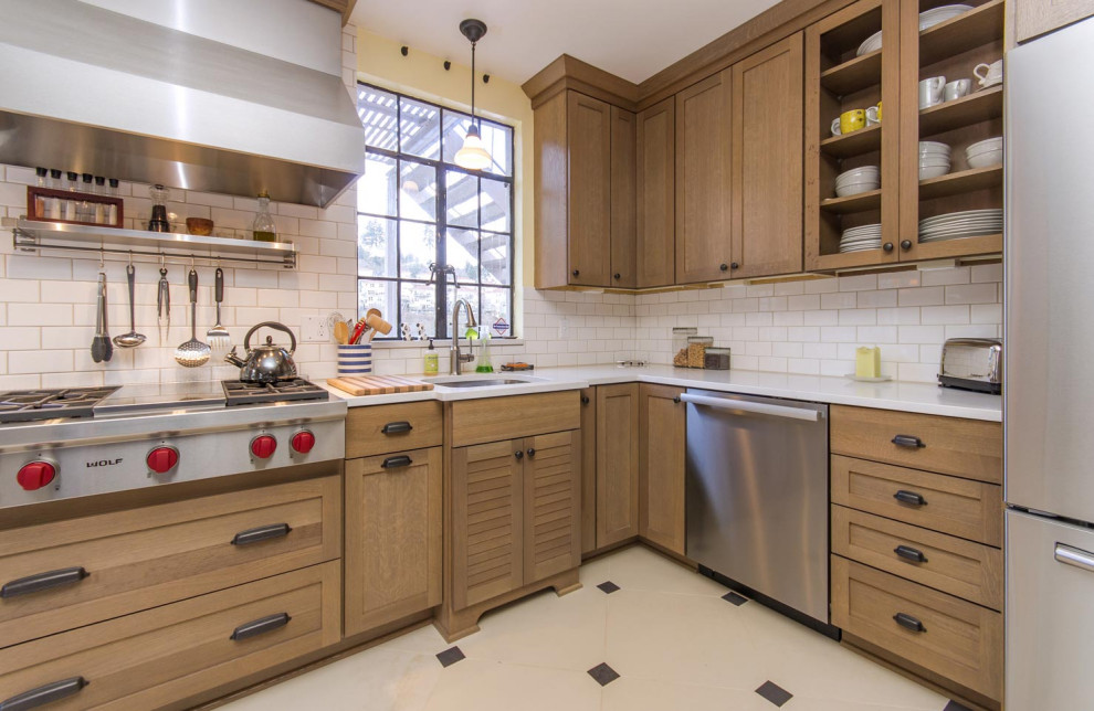 Enclosed kitchen - transitional l-shaped porcelain tile and white floor enclosed kitchen idea in Portland with an undermount sink, shaker cabinets, light wood cabinets, solid surface countertops, white backsplash, ceramic backsplash, stainless steel appliances, an island and white countertops