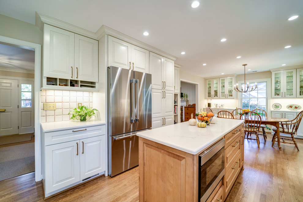 This is an example of a large traditional u-shaped kitchen in DC Metro with a submerged sink, raised-panel cabinets, white cabinets, marble worktops, stainless steel appliances and an island.