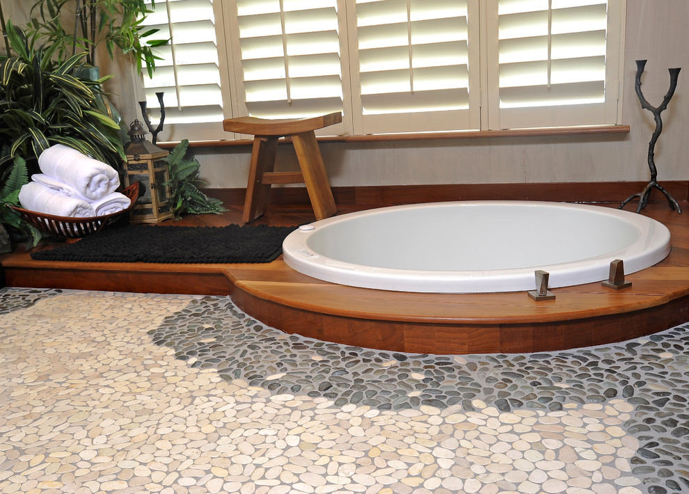 This is an example of a mid-sized asian bathroom in Other with a vessel sink, flat-panel cabinets, distressed cabinets, wood benchtops, a drop-in tub, a wall-mount toilet, multi-coloured tile, stone tile, beige walls, pebble tile floors, with a sauna and a corner shower.