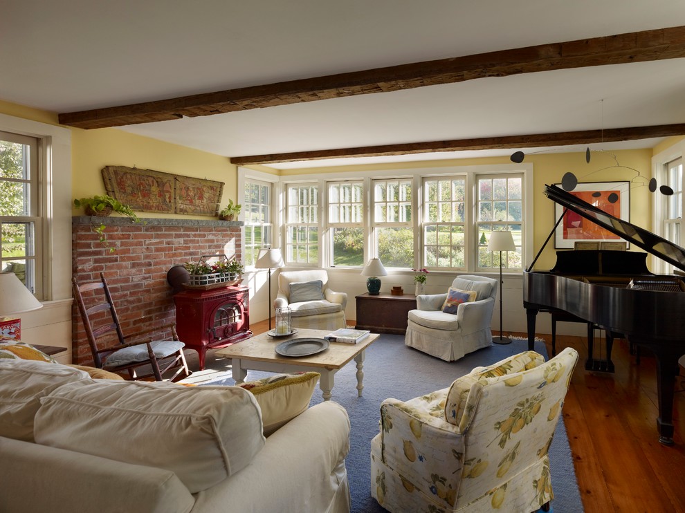 Inspiration for a mid-sized eclectic enclosed family room in Boston with a music area, yellow walls, medium hardwood floors, a standard fireplace and a brick fireplace surround.