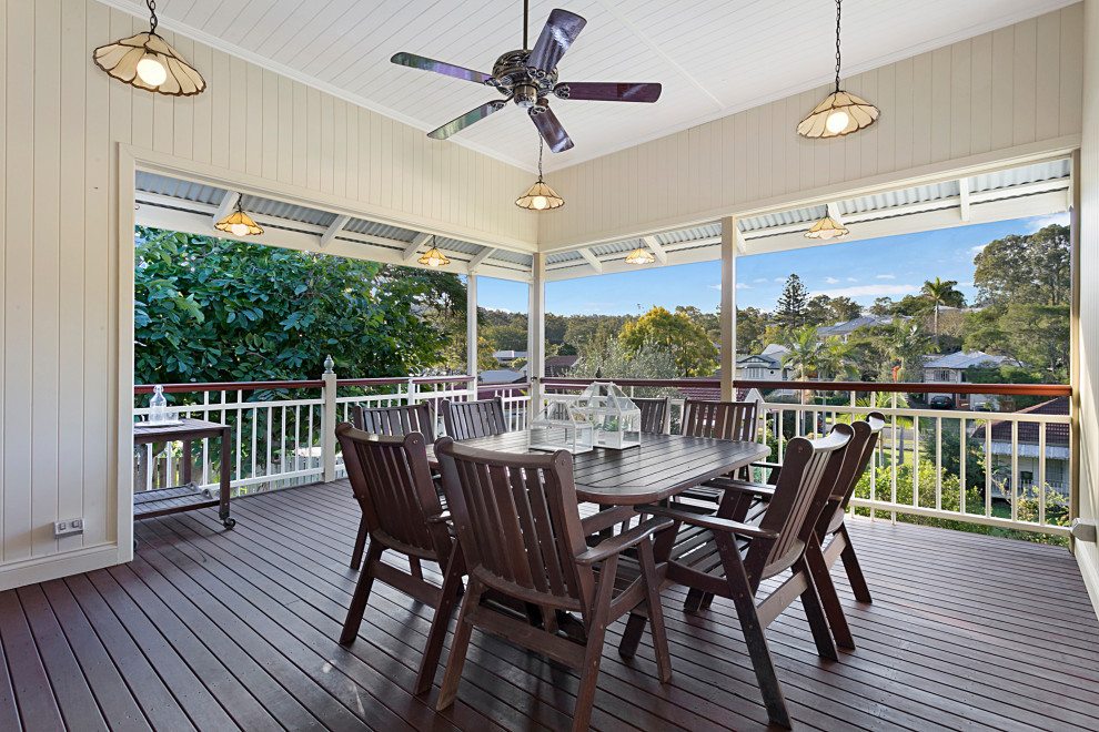 This is an example of a large traditional backyard and first floor deck in Brisbane with with skirting, a roof extension and wood railing.
