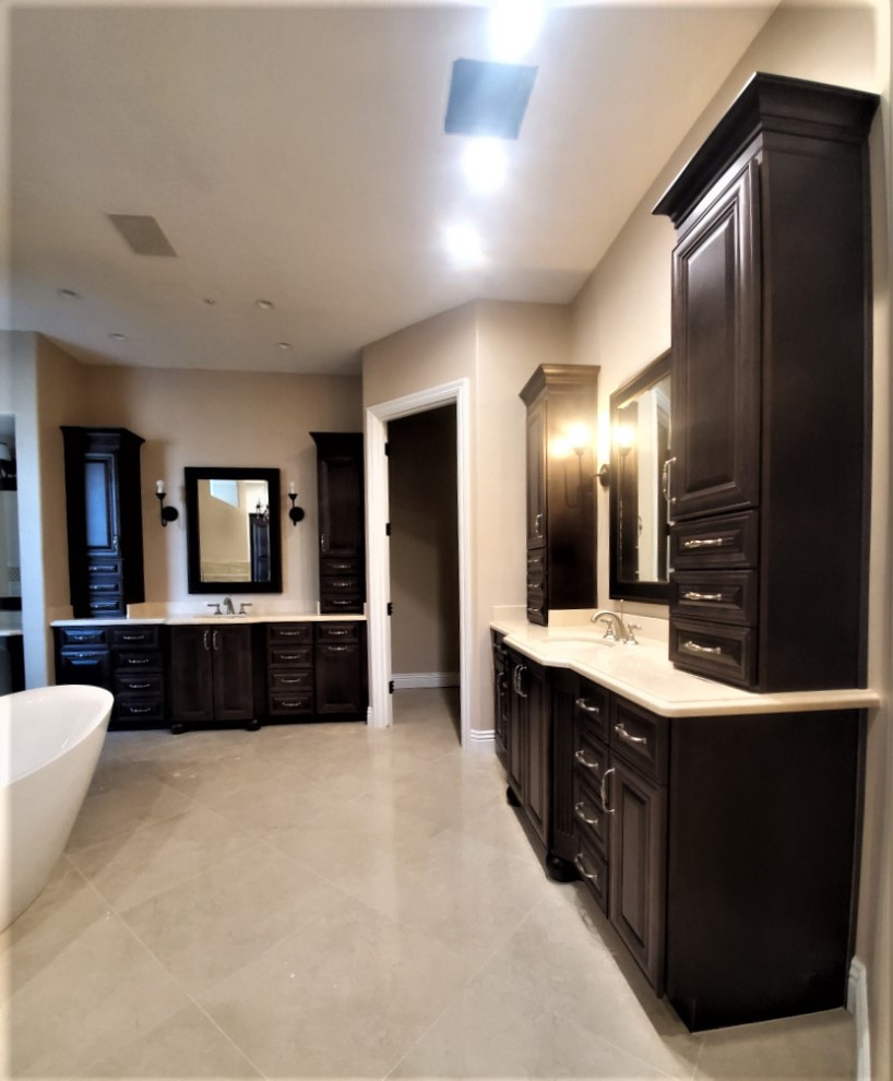 This is an example of an expansive traditional master bathroom in Phoenix with raised-panel cabinets, dark wood cabinets, a freestanding tub, an alcove shower, white tile, beige walls, an integrated sink, granite benchtops, a hinged shower door, white benchtops, a double vanity, a floating vanity, a one-piece toilet, ceramic floors, beige floor and an enclosed toilet.