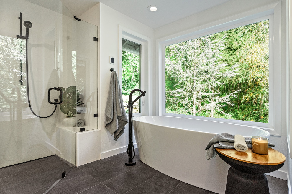 Photo of a mid-sized modern master bathroom in Portland with flat-panel cabinets, brown cabinets, a freestanding tub, a curbless shower, a wall-mount toilet, white tile, white walls, an undermount sink, quartzite benchtops, black floor, a hinged shower door, grey benchtops, a shower seat, a double vanity and a floating vanity.