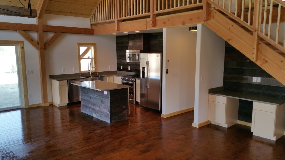 Small country l-shaped separate kitchen in Seattle with a farmhouse sink, shaker cabinets, white cabinets, stainless steel benchtops, brown splashback, timber splashback, stainless steel appliances, medium hardwood floors, with island and brown floor.